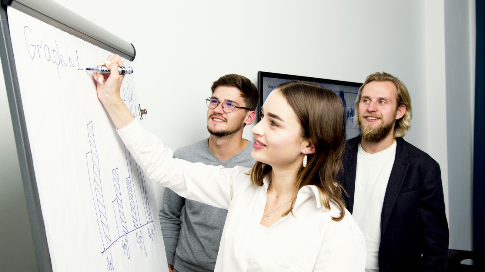 Drei Fachleute arbeiten an einer Geschäftspräsentation mit Diagramm in einem Büro.